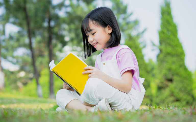 Image of Asian little girl studying at park
